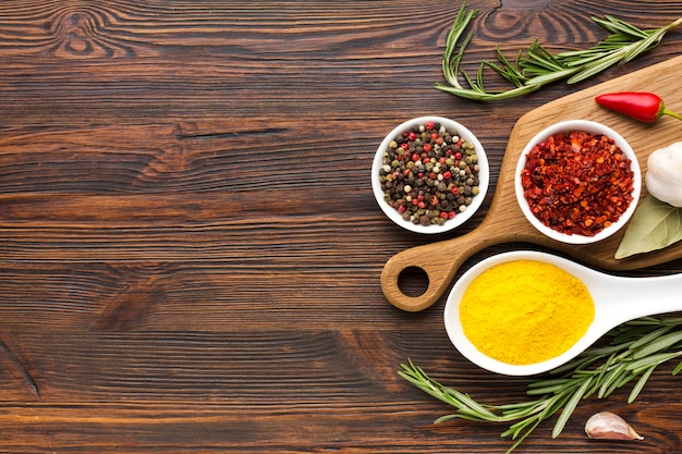 Spices on spoon and bowls on wooden table