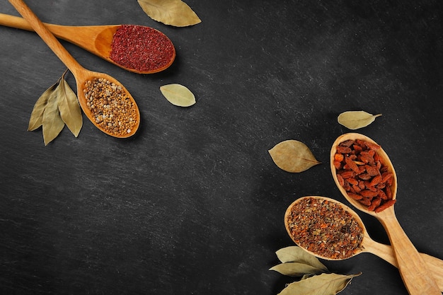 Photo spices in wooden spoons on a dark background