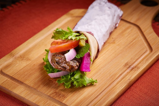 Spicy arabian kabab shawarma wrap with salad served in dish isolated on table side view