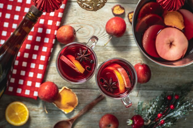 Spicy aromatic hot mulled wine in a saucepan and a clear glass on a wooden table with festive accessories. Concept of a cozy holiday atmosphere, New Year and Christmas mood. Top view.