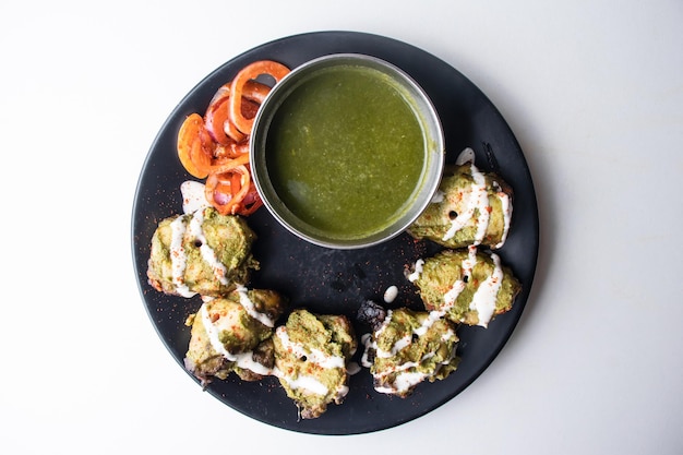 Spicy bbq Chicken Hariyali tikka boti Kebab or green chicken kabab with chili sauce served in a dish isolated on grey background top view of bangladesh food