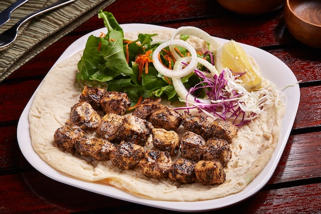 Spicy bbq Chicken Tikka boti kabab with bread lemon and salad served in dish isolated on table side view of middle east food