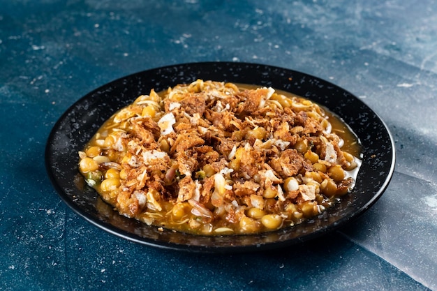 Spicy Chana chat masala chotpoti in a black dish isolated on background top view of indian bangali and pakistani food chat pata food