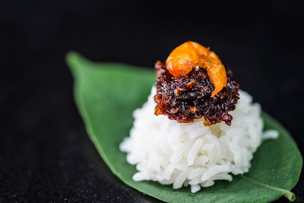 Spicy chili paste with steamed rice on dark wall