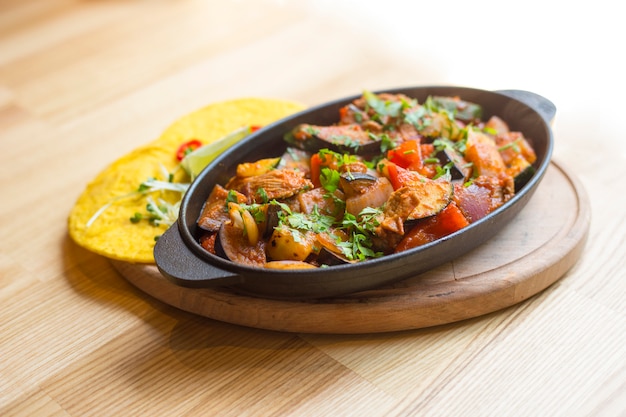 Spicy fajitos in cast iron pan and corn tortillas on wooden table. Mexican food. Mexican dish