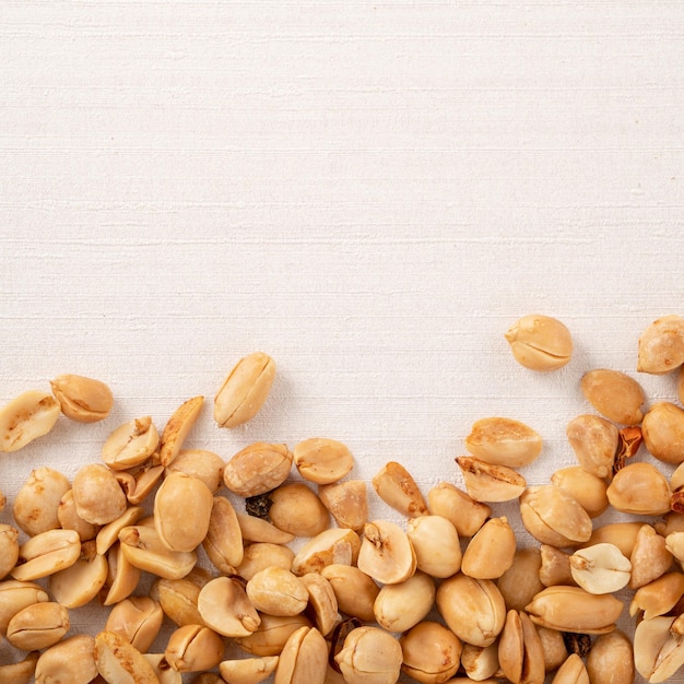 Spicy flavored peanut kernel spilling on white table background