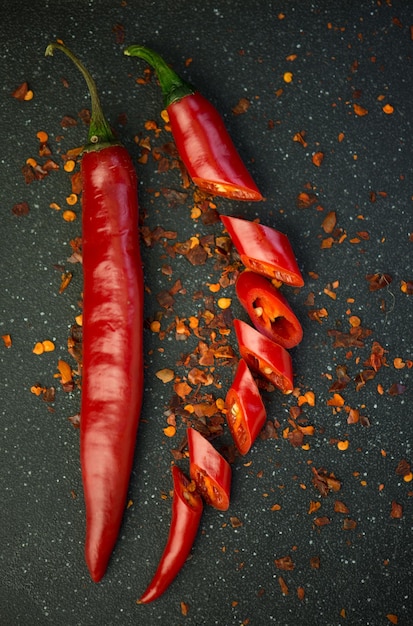 Spicy food Red chili pepper cut into pieces on a black background Hot spice red chili and chili powder