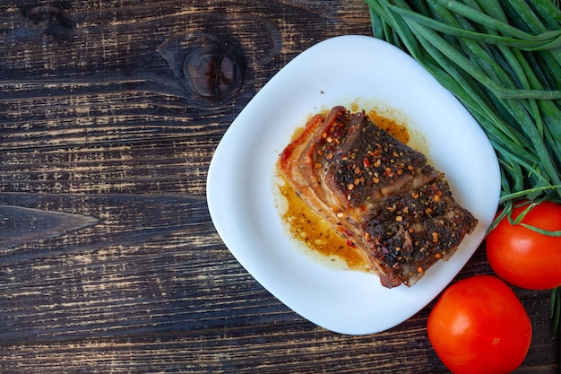 Spicy fried brisket with layers of bacon baked with herbs and paprika with red tomatoes and onions