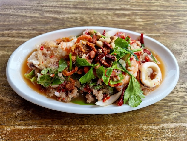 Spicy Glass Noodle Salad with prawn and calamari on wooden table