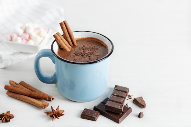 Spicy hot chocolate with cinnamon and star anise in enamel blue mug on white background