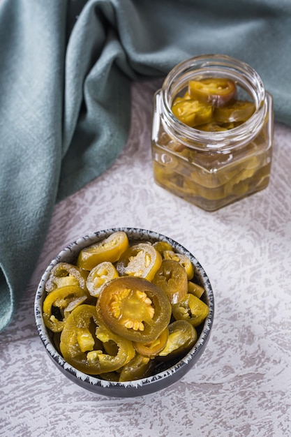 Spicy mexican pickled jalapeno peppers in bowl and glass jar vertical view