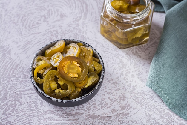 Spicy mexican pickled jalapeno peppers in bowl and glass jar