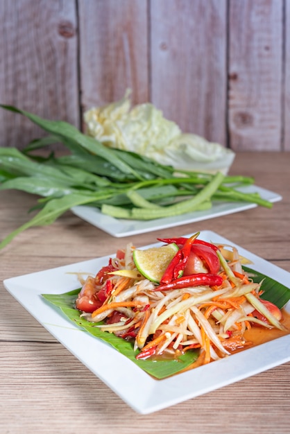 Spicy papaya salad on a dish with side of fresh vegetables