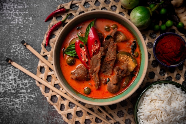 Spicy pork red curry with jasmine rice and curry paste on a wooden plate   - Thai food side dish