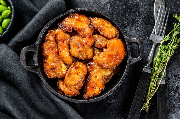 Spicy pork in sweet and sour sauce in a pan. Black background. Top view