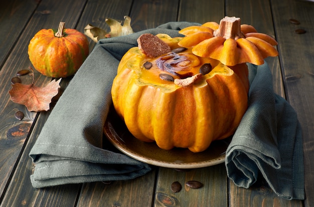 Spicy pumpkin soup served on a dark wood in a hollowed pumpkin