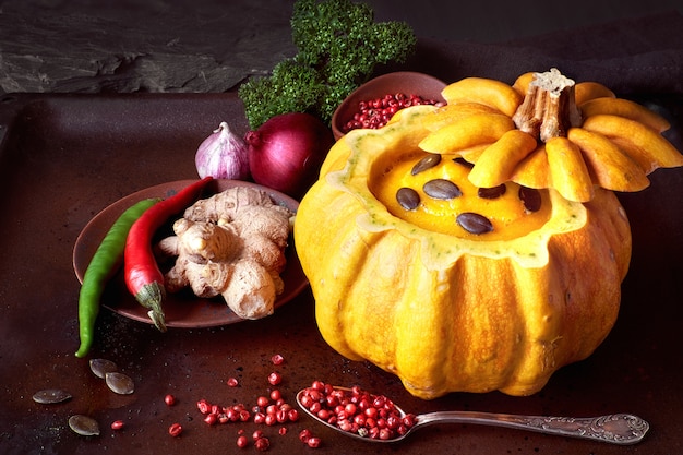 Spicy pumpkin soup served in a hollowed pumpkin on dark