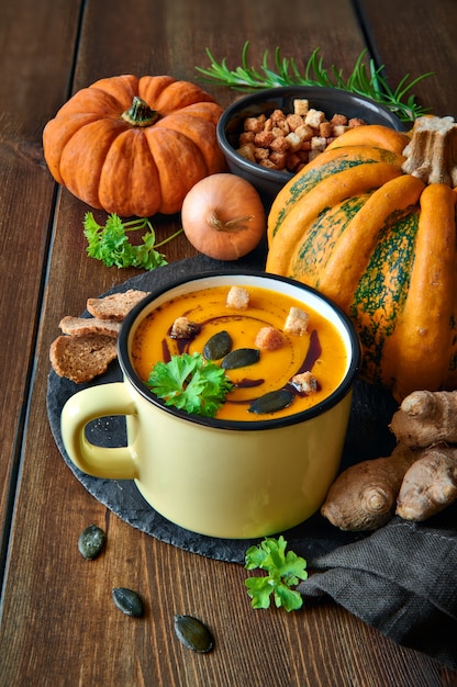 Spicy pumpkin soup with ginger and onion, served in mug with pumpkin oil