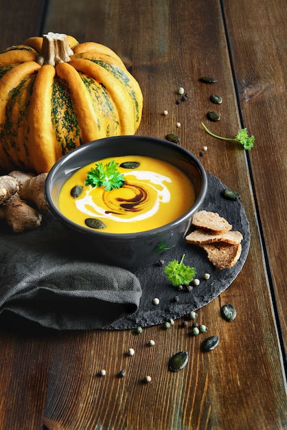 Spicy pumpkin soup with ginger and parsley served on dark wood