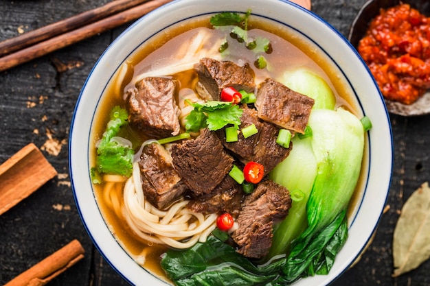 Spicy red soup beef noodle in a bowl on wooden table