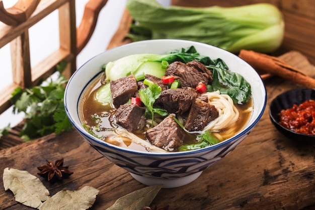 Spicy red soup beef noodle in a bowl on wooden table