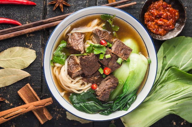 Spicy red soup beef noodle in a bowl on wooden table