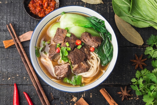 Spicy red soup beef noodle in a bowl on wooden table