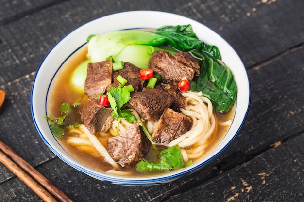 Spicy red soup beef noodle in a bowl on wooden table