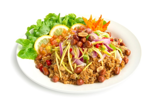 Spicy Salad Crispy Catfish with mango slice hot tasty food of Thai on top fried peanuts decorate with green oak chili carved and lemon side view isolated on white background