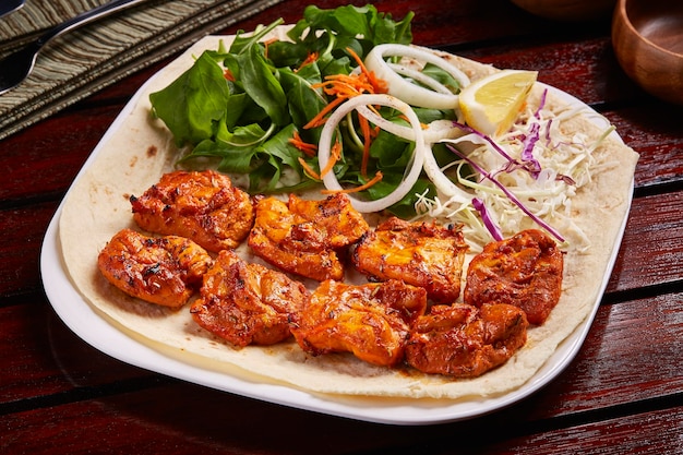 Spicy Sheesh Tawook or shish tikka boti kebab with salad lemon and bread served in dish isolated on table side view of middle east food