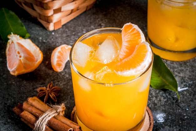 Spicy winter tangerine Cocktail with vodka, fresh tangerines, cinnamon and anise, on dark background, copy space