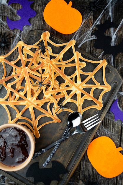 Spiders on homemade web-shaped pancakes for Halloween. Scary halloween. View from above. Close-up.