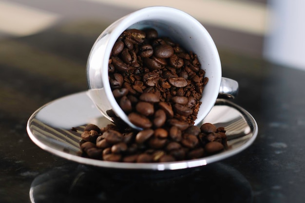 Photo spilled coffee beans cup and saucer