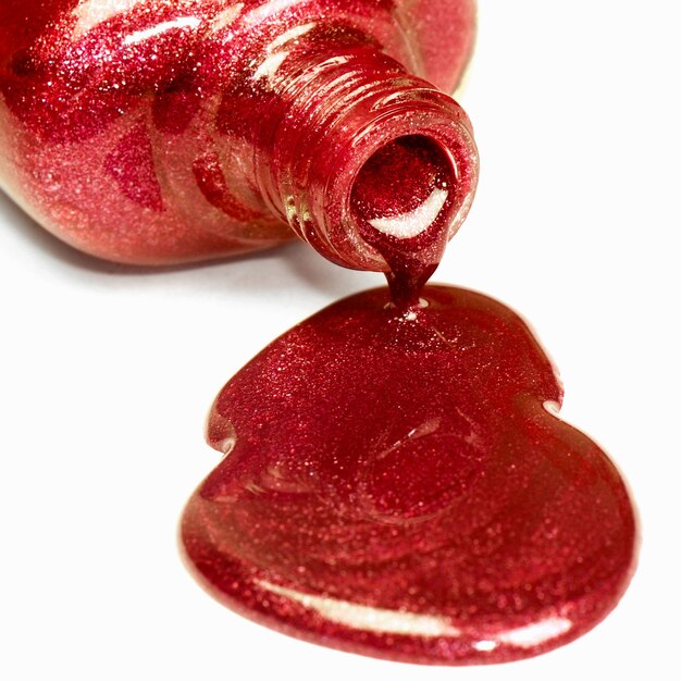 The spilled red nail polish is on white background.