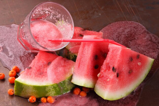 Spilled watermelon cocktail with watermelon slices on dark background Healthy food concept sweet summer dessert Closeup