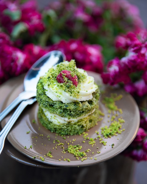 Spinach pastry on the brown little plates and two teaspoons on it. A bouquet of roses as a background.