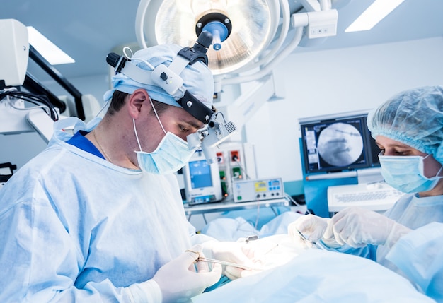 Spinal surgery. Group of surgeons in operating room with surgery equipment.