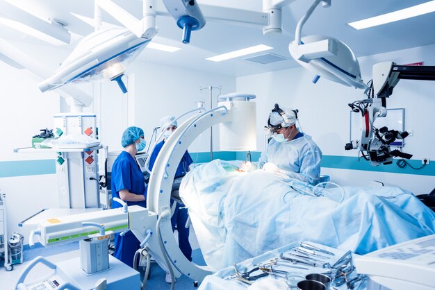 Spinal surgery. Group of surgeons in operating room with surgery equipment. 