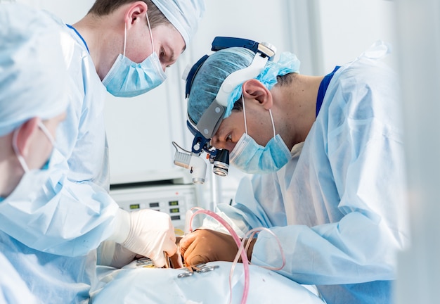 Spinal surgery. Group of surgeons in operating room with surgery equipment.