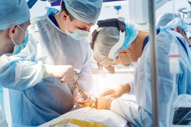 Spinal surgery. Group of surgeons in operating room with surgery equipment.