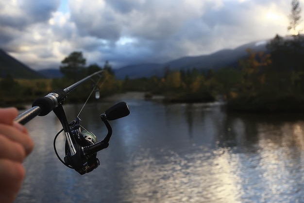 spinning reel in hand fishing nature, abstract background, hobby vacation man