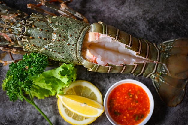 Spiny lobster sashimi seafood fresh lobster or rock lobster with herb and spices lemon parsley on dark background raw spiny lobster for cooking food