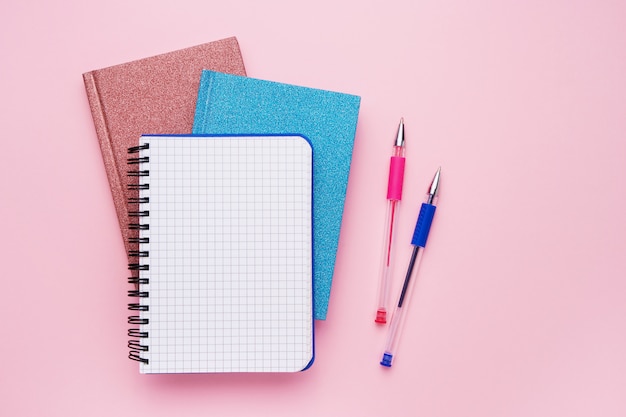 Spiral notepad with pens as mockup for your design on pink. Back to school concept. Copy space, top view.