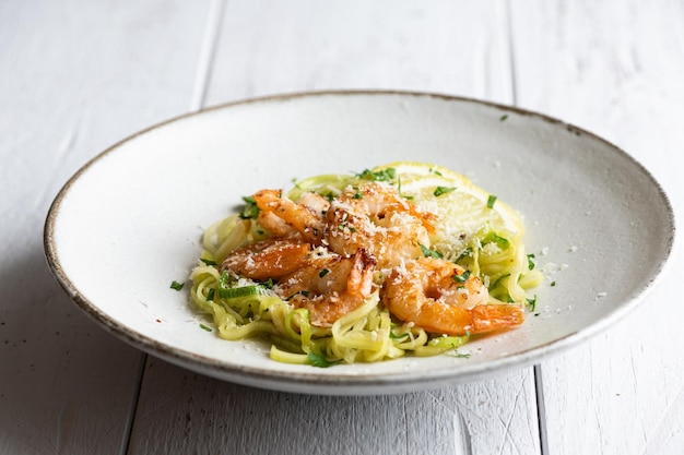 Spiralized zucchini noodles pasta with shrimps on gray background selective focus