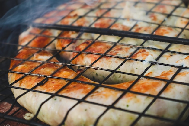 Spirals of spicy sausage grilling on a BBQ over hot flaming coals Grilled natural spiral meat sausage