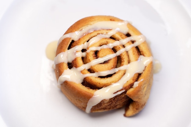 Spiralshaped pastry decorated with white cream on top in a white background