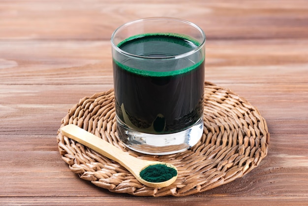 Spirulina drink in a glass on a brown wooden table