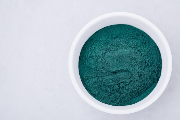 Spirulina Green algae powder chlorella spirulina in bowl on gray stone background