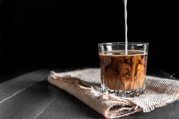 Splash of ice coffee drink on a brown background. cup with ice cubes. Cold beverage wave. Close-up design liquor milk, coffee and ice. cream is poured into the Cup