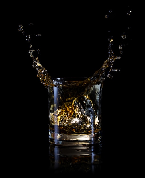 Splash of ice in a glass of whiskey